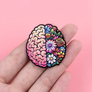 Pin’s santé mentale cerveau fleuri présenté dans une main