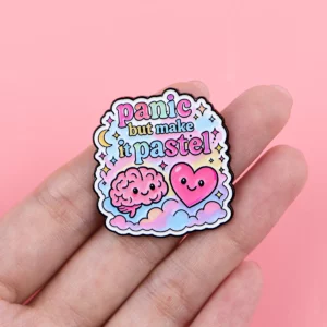 Pin’s santé mentale Panic but Make It Pastel tenu dans une main