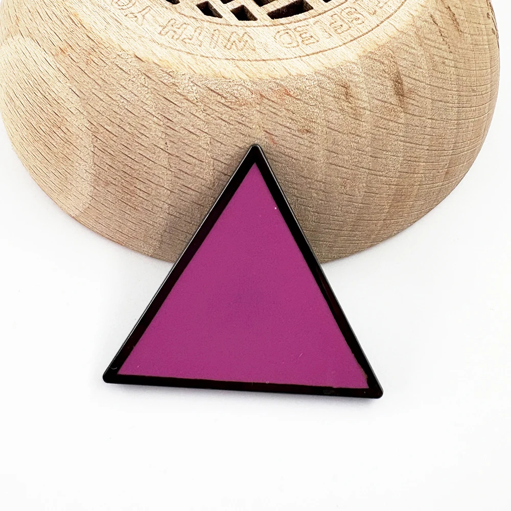 Pin’s LGBTQIA+ triangle rose sur décor en bois